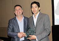 PPhoto of two men posing for a picture. The man on the right is holding an award.