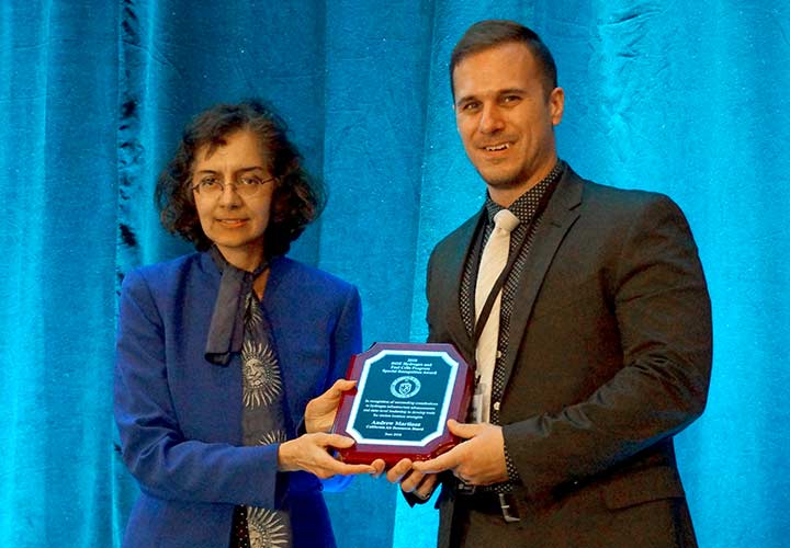 Sunita Satyapal presents an award plaque to Andrew Martinez.