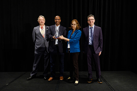 Four people stand with an award trophy.